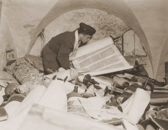 Chaplain Samuel Blinder examines one of the Torah scrolls stolen by the Einsatzstab Rosenberg and stored in the basement of the Institut fuer Juedische Erforschung (Institute for Research into the Jewish Question) in Frankfurt am Main